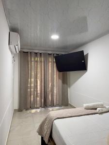 Orilla beach house في Playa Punta Arena: غرفة بها سرير وتلفزيون على الحائط