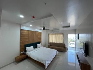 a bedroom with a bed and a couch and a television at Hotel Lotus Suites in Miraj