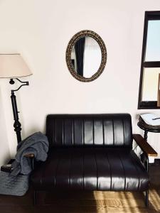 a black leather couch in a living room with a mirror at Maison Petit Lapin メゾンプチラパン in Karuizawa