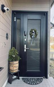 Maison Petit Lapin メゾンプチラパン في كارويزاوا: باب امامي اسود عليه اكليل