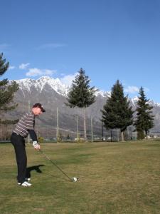 a man playing golf in a field with mountains in the background at Remarkable studio,close to airport in Queenstown