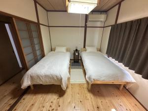 zwei Betten in einem Zimmer mit Holzboden in der Unterkunft MIYABI stay house in Tamana
