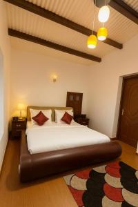 een slaapkamer met een groot wit bed met rode kussens bij Secret Escape Heritage Bungalow in Ooty +19 foto's