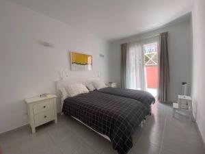 Apt. El Guirre Nº 8 - bajo في La Playa Calera: غرفة نوم بيضاء مع سرير ونافذة