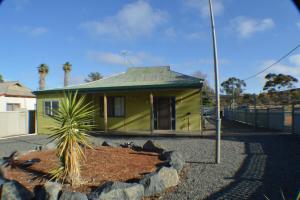 a yellow house with a palm tree in front of it at Norseman AirbnbAngels Place in Norseman
