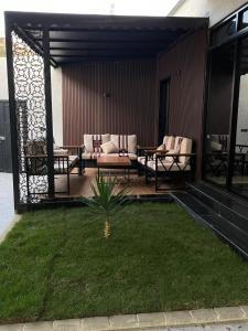 un patio con divani, tavoli ed erba di شاليه لوسيندا a Baljurashi