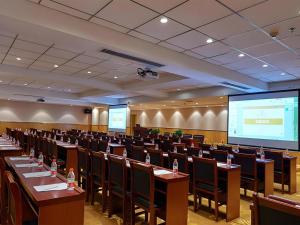 a conference room with tables and chairs and a projection screen at Vienna Hotel Shandong Qufu Sankong Landscape in Qufu