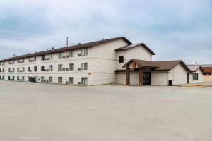 a large white building with a parking lot at Super 8 by Wyndham Williston ND in Williston