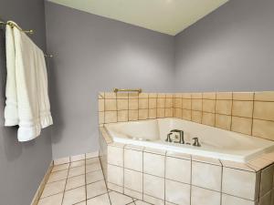 a bathroom with a tub and a tiled floor at Super 8 by Wyndham Williston ND in Williston +30 photos