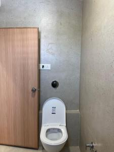 a bathroom with a toilet and a wooden door at Hotel Sun Shine in Jāmb