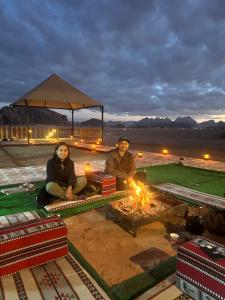 a man and a woman sitting next to a fire at WADI RuM GRAND in Wadi Rum