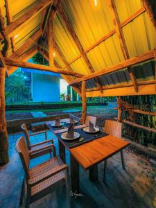 Un comedor con mesa y sillas de madera. en Cinnamon River Edge, en Udawalawe