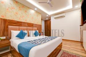a bedroom with a large bed with blue pillows at Olivia Hotels - Delhi Airport in New Delhi