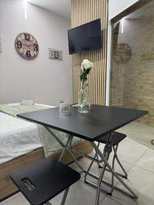 a black table with a vase of flowers and a clock at Sams Room in Catania