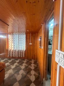 Una habitación con techo de madera y suelo de cuadros. en Shyam home stay URBAN Cafe, en Nārkanda