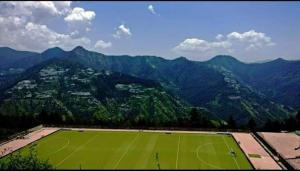 una pista de tenis con montañas al fondo en Shyam home stay URBAN Cafe, en Nārkanda