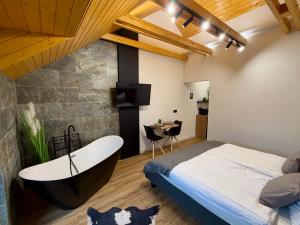 a bedroom with a tub and a bed and a table at Csuszka Vendégház MÁTRA in Mátraszentimre +24 photos