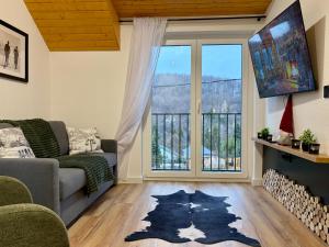 a living room with a couch and a large window at Csuszka Vendégház MÁTRA in Mátraszentimre