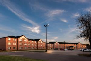 a parking lot in front of a large brick building at Days Inn & Suites by Wyndham Des Moines Airport in Des Moines