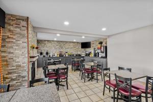 a restaurant with tables and chairs and a kitchen at Days Inn & Suites by Wyndham Des Moines Airport in Des Moines