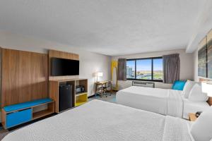 a hotel room with two beds and a flat screen tv at Days Inn & Suites by Wyndham Des Moines Airport in Des Moines +78 photos
