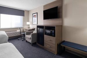 a hotel room with a television and a bed and a desk at Baymont by Wyndham Davenport in Davenport