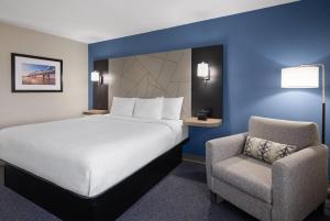 a hotel room with a bed and a chair at Baymont by Wyndham Davenport in Davenport +46 photos