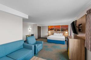 a hotel room with a bed and a blue couch at Days Inn & Suites by Wyndham Des Moines Airport in Des Moines