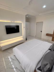 a white bedroom with a large bed and a flat screen tv at Apo Luxe 3-Bedroom Apartment in Garki