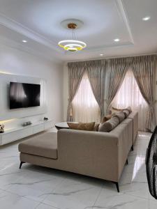 a living room with a couch and a flat screen tv at Apo Luxe 3-Bedroom Apartment in Garki