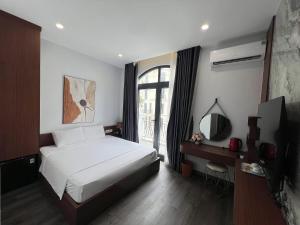 a bedroom with a bed and a television and a window at Kapás Hotel in Hai Phong