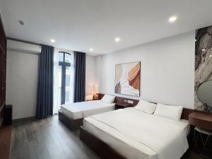 a hotel room with two beds and a window at Kapás Hotel in Hai Phong