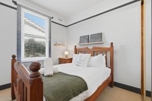 a bedroom with a wooden bed and a window at Poets View - 3 Bedroom House in West Hobart