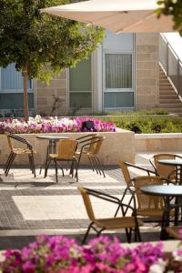 eine Gruppe von Tischen und Stühlen in einem Innenhof mit Blumen in der Unterkunft Ein Kerem Hotel in Jerusalem