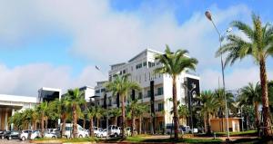 a building with palm trees in front of a parking lot at The O Valley Hotel in Ban Tha Phala Nua