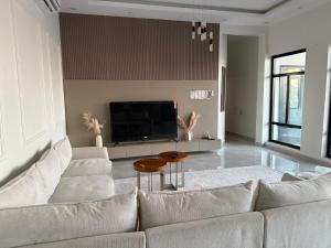 a living room with a white couch and a tv at H chalet in ‘Uqdah