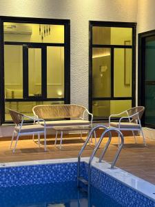 two chairs and a table next to a swimming pool at H chalet in ‘Uqdah