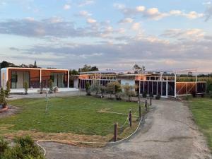 un bâtiment avec un champ devant lui dans l'établissement LeLaNa Farmstay Camping, à Pak Chong