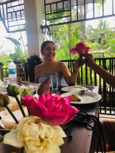 a woman sitting at a table holding up flowers at Lotus cool hotel and restaurant in Ibbagomuwa