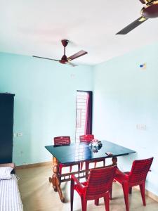a dining room with a table and two red chairs at Pranavam Beach Homestay in Alleppey