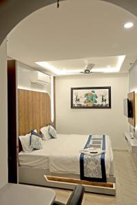 a bedroom with a bed and a tv on a wall at Hotel VD Rooms in Surat