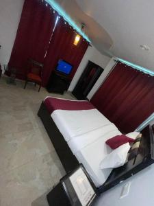 a bedroom with a large white bed with red curtains at Dharamshala Naddi Edge sunset point# Free Parking-cricket stadium 10 km-Mcleodganj 2 km- Bhagsunag 4 in Dharamshala