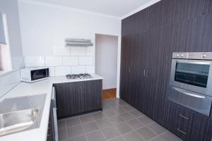 a kitchen with a stove, microwave and refrigerator at Wilsonton Hotel Toowoomba in Toowoomba