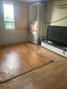 a living room with a flat screen tv and a wooden floor at Seven Motel in Busan