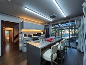 Ogiファミーユ 一碧湖 湖近く 温泉 屋根付バーベキューテラス 1棟貸切宿的一个带酒吧椅的大岛厨房