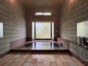 Ogiファミーユ 一碧湖 湖近く 温泉 屋根付バーベキューテラス 1棟貸切宿的一间带浴缸的浴室,位于一个窗口的房间