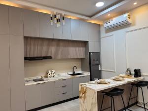 a kitchen with white cabinets and a counter with stools at H chalet in ‘Uqdah