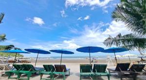 a group of chairs and blue umbrellas on a beach at Blue Wave Hotel Hua Hin in Hua Hin