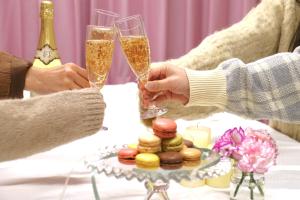 two people holding champagne glasses at a table with donuts at 一棟貸しゲストハウス マリドール in Izumo
