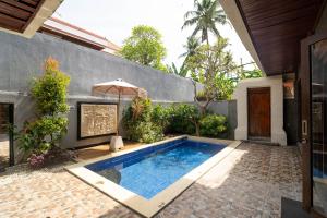 a swimming pool with an umbrella next to a house at Kayangan Saba Villa in Keramas